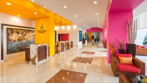 韦拉克鲁斯卡米诺睿尔韦拉克鲁斯酒店的大堂设有粉红色和黄色的墙壁和椅子