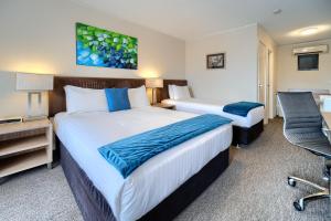 奥尔巴尼Albany Motel & Apartments的酒店客房配有两张床和一张书桌