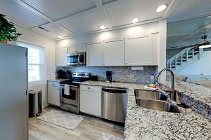 卡罗来纳比奇Oceanfront Townhouse的厨房配有白色橱柜和不锈钢用具