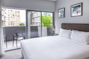 悉尼Holiday Inn & Suites Sydney Bondi Junction, an IHG Hotel的一间带一张白色大床的卧室和一个阳台