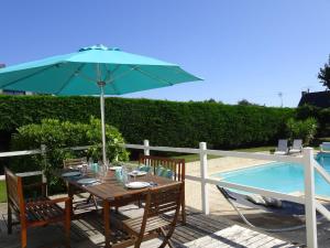 GouesnachHoliday home with private outdoor pool, Gouesnac"h的游泳池旁带遮阳伞的桌子