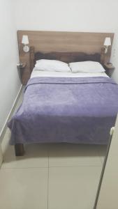 瓜鲁雅Hotel Morada do Mar的一张带紫色毯子和两个枕头的床