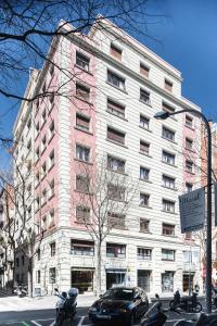 巴塞罗那Mercedes Heritage Apartments的一座粉红色和白色的建筑,前面有停车位