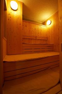 苫小牧市多美迎苫小牧酒店的一间设有木镶板墙和两个灯的桑拿浴室