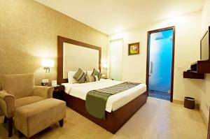 新德里The Grand Vikalp By Saga Hotels的一间卧室配有一张床、一把椅子和镜子