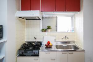 名古屋stay's サンジョイフル 303号 名古屋 民泊 駅近的厨房配有红色橱柜、水槽和炉灶。