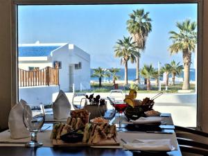 迪巴Holiday Beach Resort的一张桌子,配有食物和酒杯,享有海滩美景