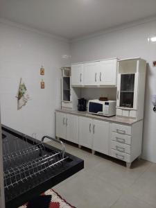 马林加Ótimo apartamento sobreloja com wifi e estacionamento incluso的厨房配有白色橱柜和微波炉