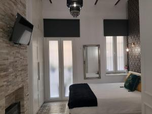 塞维利亚LA SUITE DEL CONDE LUXURY SUITES的一间卧室设有一张带壁炉和电视的床。