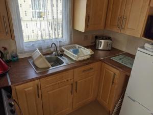 Lincolnshire8 Berth Northshore (The Westmorland)的厨房配有木制橱柜、水槽和冰箱。