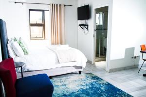 BizanaHappy Hen Guest Lodge的卧室配有白色的床和蓝色地毯。