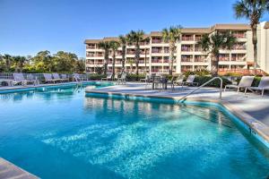 希尔顿黑德岛Bright Beach Condo on 50-Acre Hilton Head Resort!的一个带椅子的游泳池和一个位于酒店后面的酒店