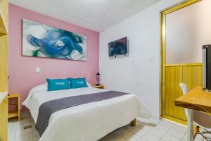 墨西哥城Ayenda Los Colorines de Coyoacán的卧室配有一张床,墙上挂有绘画作品