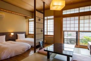伊东Toushinan Komeya的带窗户的客房内配有两张床和一张桌子