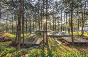 大叻Rung La Kim Resort的种有长椅和树木及花卉的公园