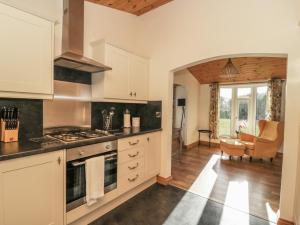 SkirpenbeckAsh Tree Lodge的厨房配有白色橱柜和炉灶烤箱。