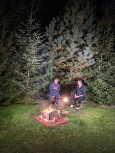 莫伊西德约斯Hotel boutique Garden Resort by Brancoveanu的两个男人在晚上坐在火坑周围