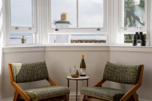 CulrossThe Dundonald Guesthouse & Cottage的带窗户的客房内配有两把椅子和一瓶葡萄酒