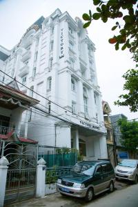 荣市Victory Hotel, số 7, Vương Thúc Mậu, Tp Vinh的停在白色建筑前面的汽车