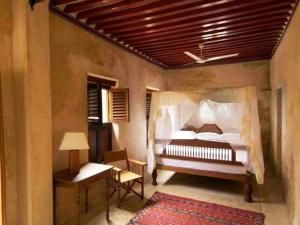 拉穆Samaki House的一间卧室配有一张床、一把椅子和一张桌子