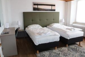 考滕巴赫Hotel Huberty Kautenbach的配有两张单人床、一张桌子和一张床的客房