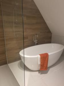 图尔奈Côté Grange的浴室配有白色浴缸,浴室设有墙壁