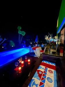 清莱Colorful Pool Villa, Chiang Rai, Thailand的游泳池在晚上配有桌子和蜡烛