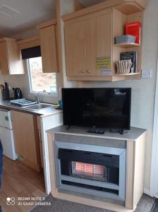 PorchfieldFamily Holiday Home - Thorness Bay - WIFI的厨房设有壁炉,配有电视。