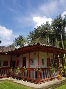 萨兰托Hostal Rio Arabia - Valle De Cocora HOTEL的一座房子,后面设有棕榈树门廊