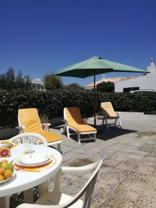 萨格里什Casa Oliveirinha - Sagres的庭院配有桌椅和遮阳伞。