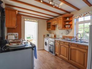 AshendonOrchard Cottage的厨房配有木制橱柜、水槽和洗碗机。