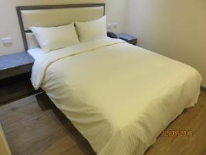 Dajia茂华商旅的一张带白色床单和枕头的床