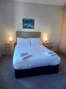 利敦瓦纳Town Square Holiday Homes的一间卧室配有一张带两盏灯的大型白色床。