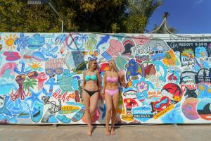 赫尔格达MinaMark Beach Resort for Families and Couples Only的两个比基尼族妇女站在涂鸦的墙上