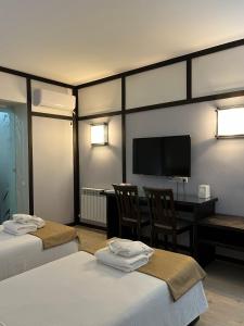 奇姆肯特Orbita hotel Shymkent的酒店客房设有两张床、一张桌子和一台电视。