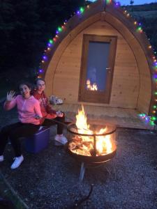 罗斯特雷弗East Coast Adventure Centre Glamping的两人坐在帐篷前,火