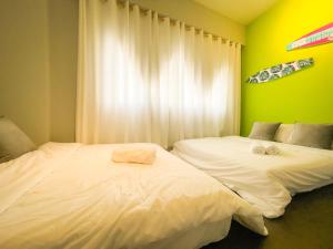 南湾垦丁南湾酒池民宿的两张床位于带绿色和黄色墙壁的客房