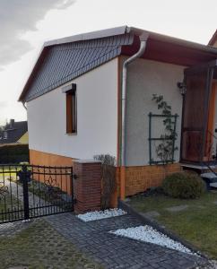 SiptenfeldeFerienhaus Harzidylle的一间白色的小房子,设有黑色的围栏