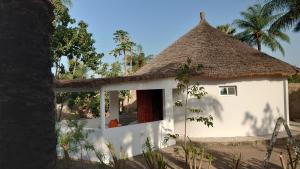 斯基灵角Case traditionnelle diola au bord de l'océan的白色的小房子,带有茅草屋顶