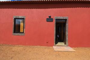 AlmagreiraQUINTA DO FALCÃO的红色的建筑,设有门和两扇窗户