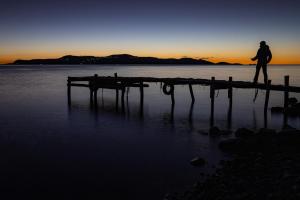 Isla de la LunaHostal Luna del Titikaka en Isla de la Luna Bolivia的日落时在水面上行走的人