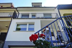 米兹多洛杰Terraced modern house in Miedzyzdroje的白色的建筑,带有红色花卉的阳台