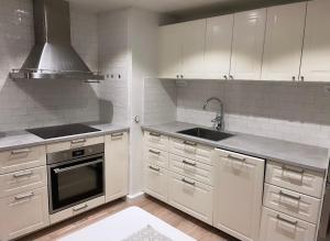 博伦厄Backes Lillstuga的厨房配有白色橱柜、水槽和炉灶。