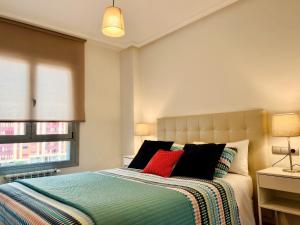 奥维多Apartamento Europa Prados - Atenea的一间卧室配有一张带两个红色枕头的床