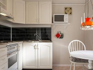 比克瑟尔克鲁克Holiday home Byxelkrok IV的厨房配有白色橱柜、桌子和时钟