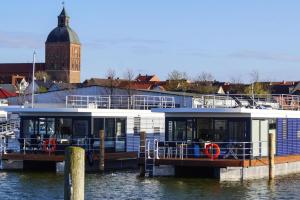 里布尼茨达姆加滕Houseboat Floating House "Luisa", Ribnitz-Damgarten的船停靠在水面上的码头