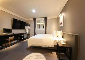 丽水市West In Hotel Yeosu的酒店客房配有一张床、一张书桌和一台电视。