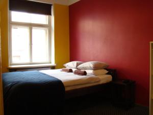 里加顽皮松鼠背包客旅舍的一间卧室设有一张红色墙壁和窗户的床