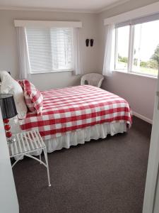TapuCoromandel Tapu - Beachfront Escape的一间卧室配有一张带红白色拼盘的床铺。