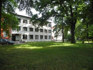 帕尔杜比采克里斯勒酒店的一座白色的大建筑,院子中有一棵树